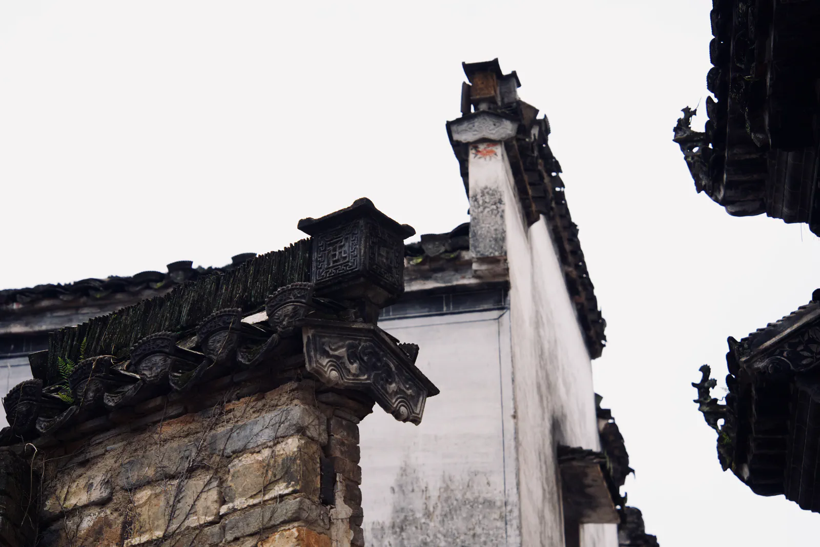 Weathered brickwork and ornate tiled eaves against a pale sky.