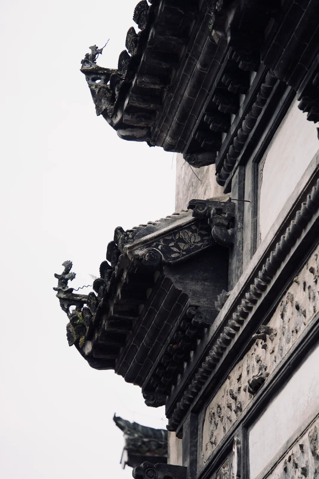A close view of carved roof details above an old white wall.