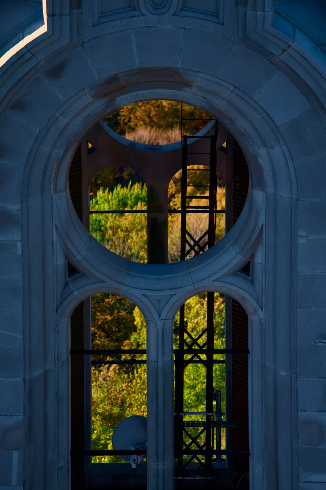 Circular and arched tower openings framing sunlit autumn trees.