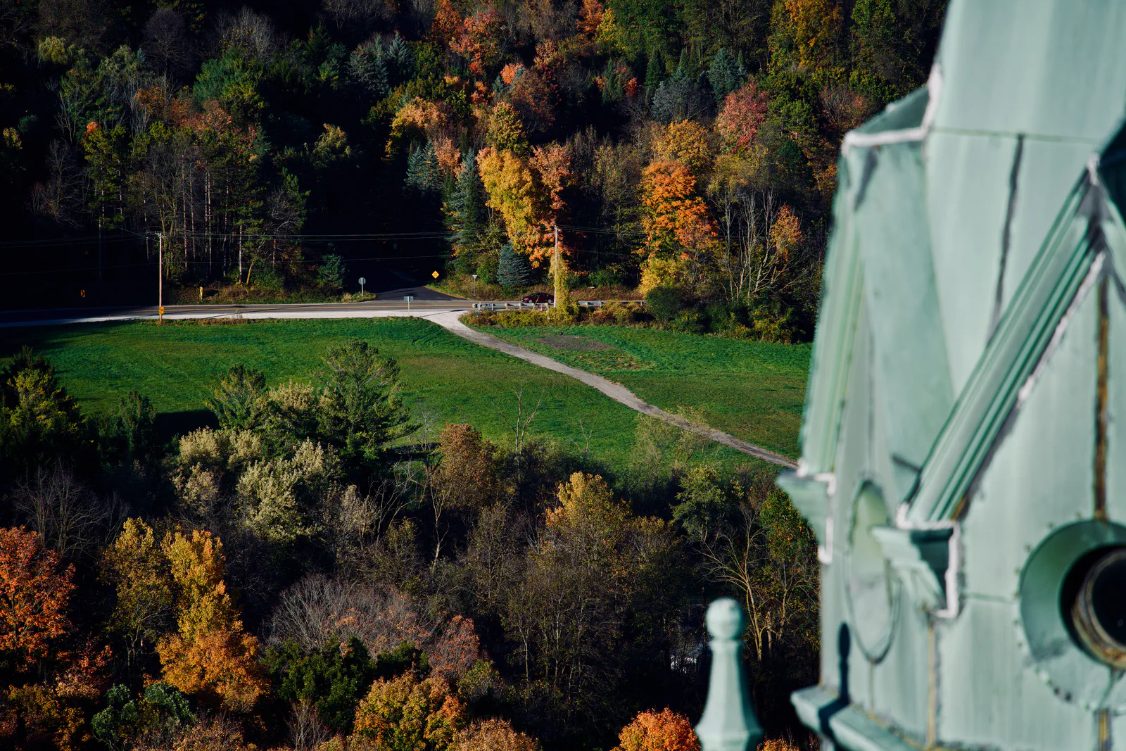 A church tower detail beside a view of a path through autumn woodland.