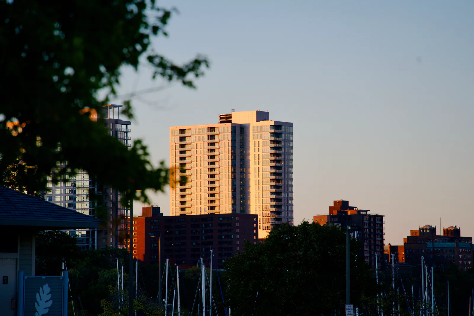 A waterfront high-rise illuminated by warm evening light.