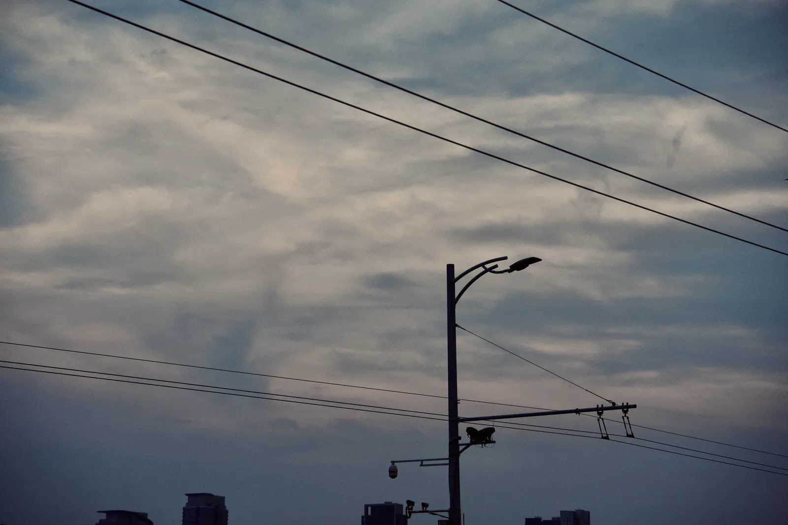 Overhead railway wires and a streetlight silhouetted against an evening sky.