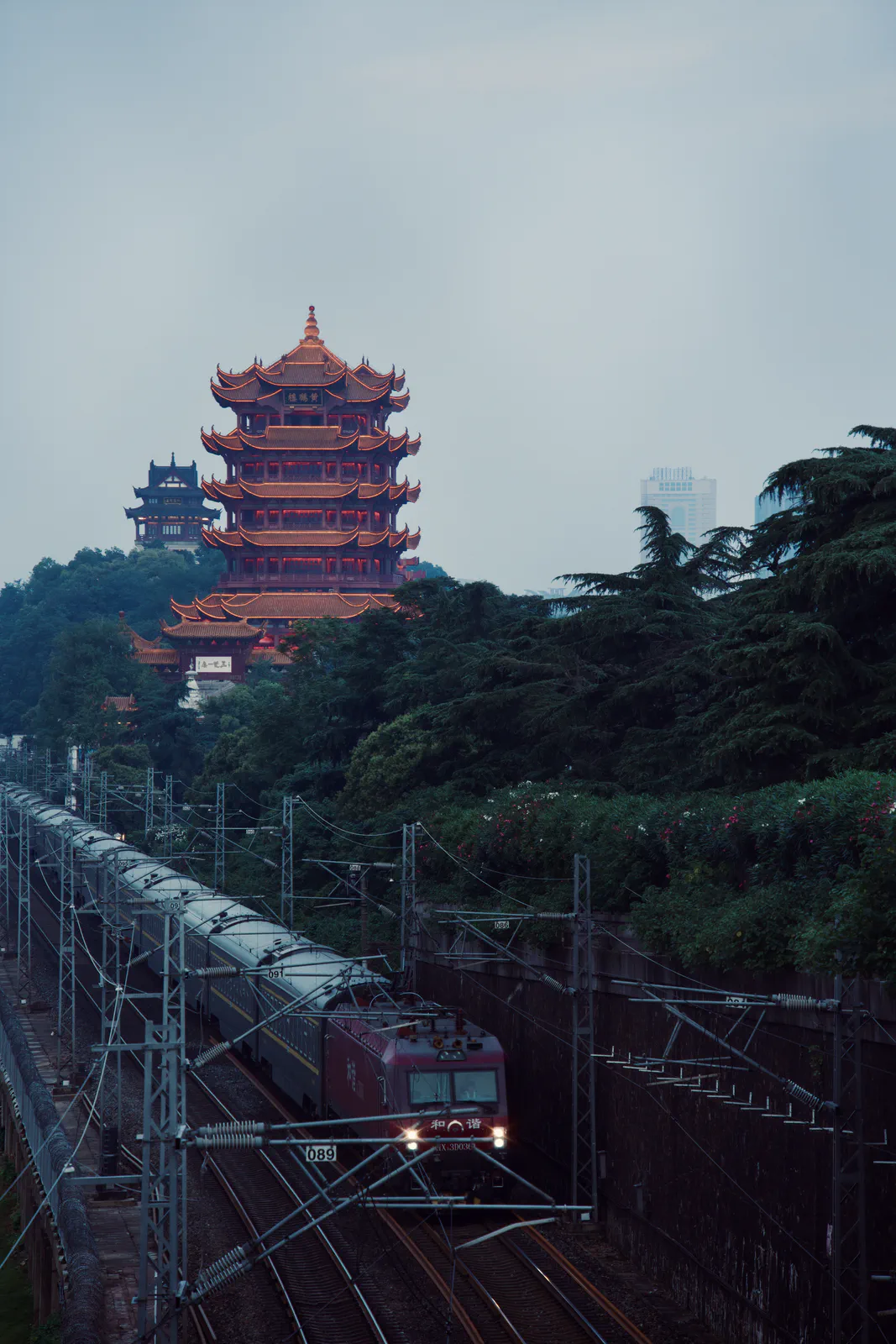 A train passing below the Yellow Crane Tower at dusk.
