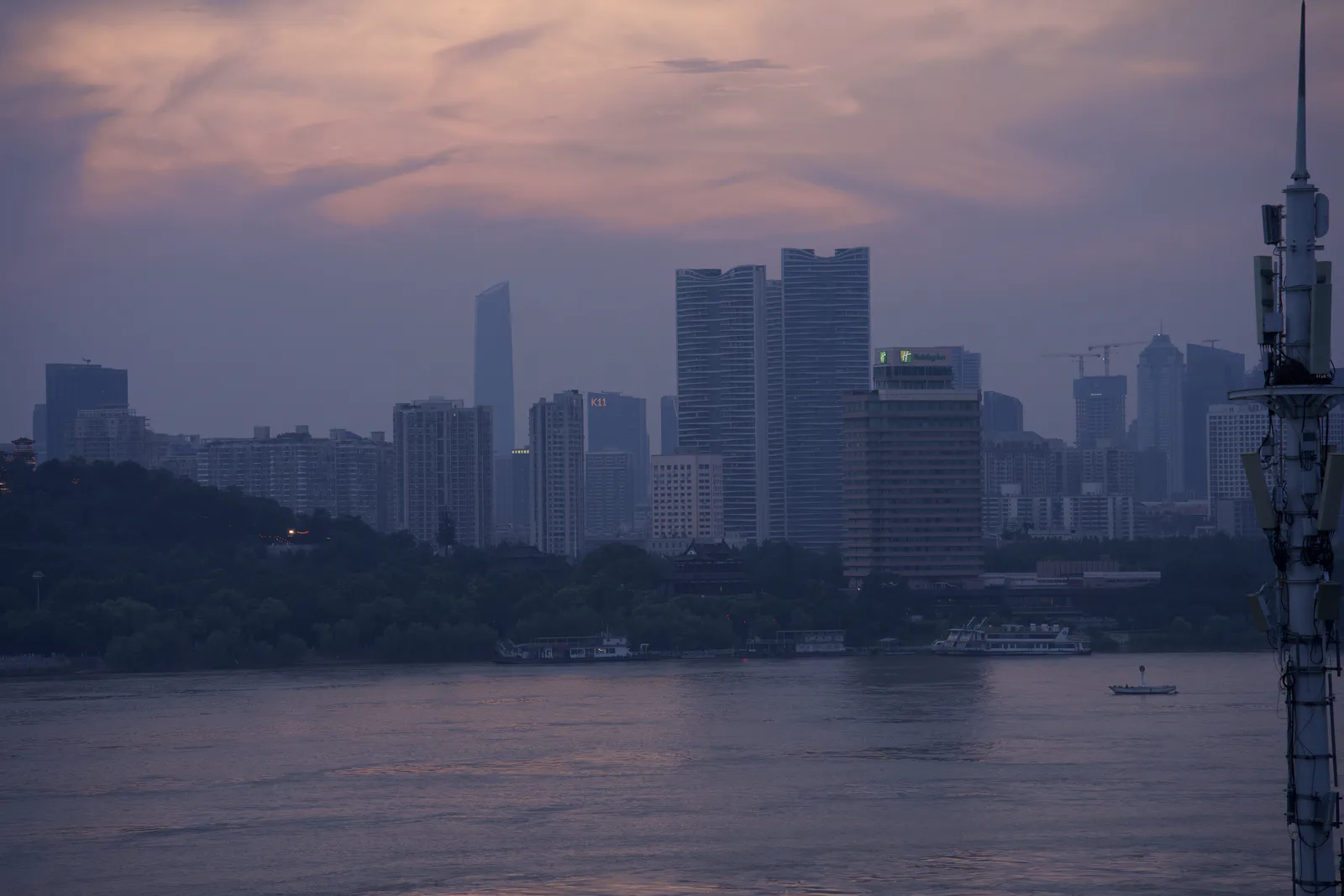 A distant city skyline across the river beneath a pink evening sky.